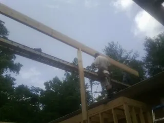 Carpenter setting a ridge beam over a new addition frame — Ice Dam Removal by Roofing Brothers in Blanch