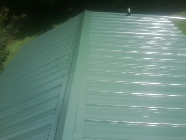New green metal panels meeting at the ridge of a roof — Flat Roof Repair work by our crew in Blanch