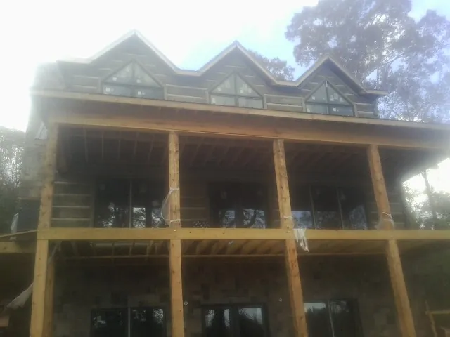Dormers and porch framing on a large log home under construction — Roof Coating work by our crew in Blanch