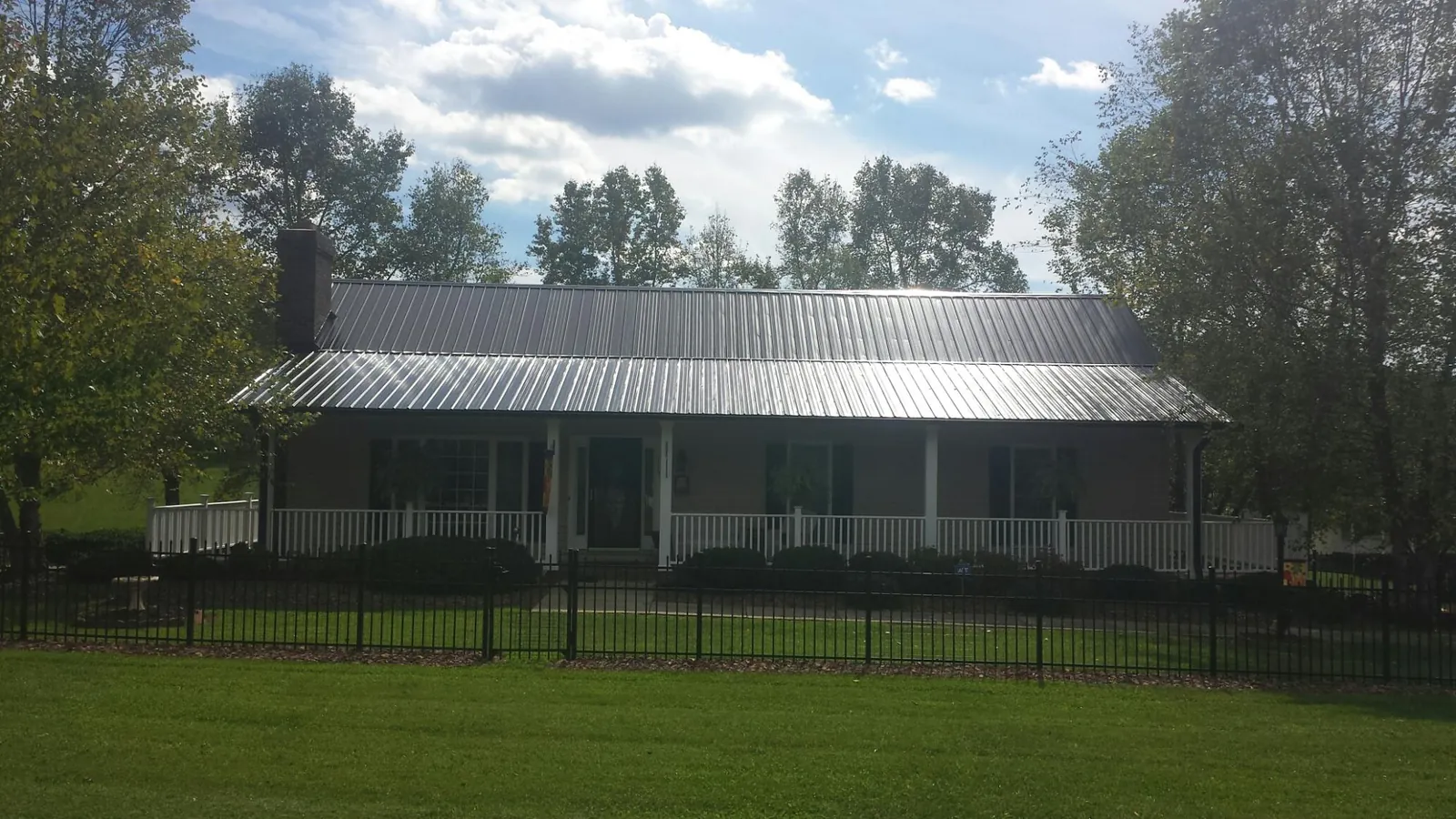 Gray metal roof on a brick ranch with a full width front porch — Gutter Guard Installation work by our crew in Blanch