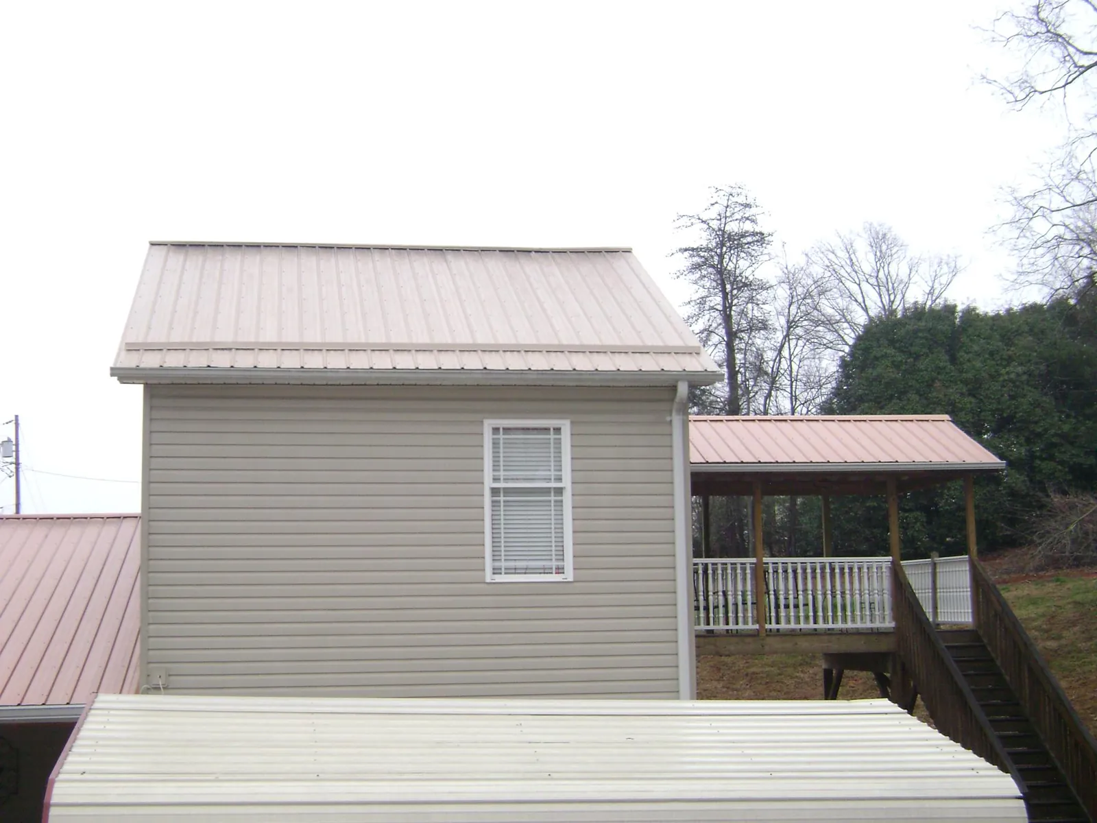 Tan metal roofs on a two story addition and attached porch, from a Roof Replacement job in Blanch